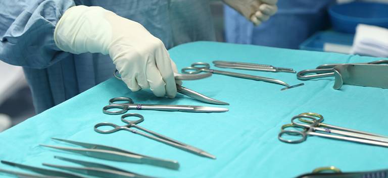 chirurg podnoszący nożyczki ze stołu
